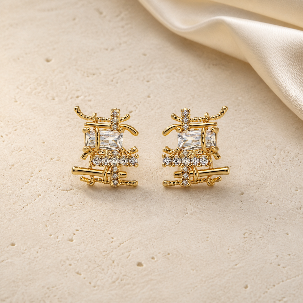 Gold woven cubic zirconia stud earrings on ivory travertine