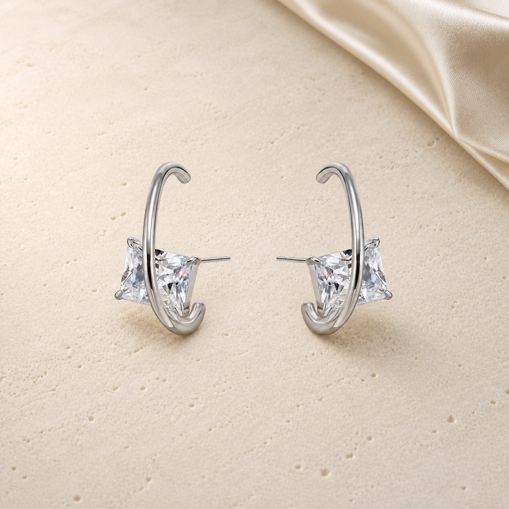 Silver wire triangular zirconia stud earrings on ivory travertine