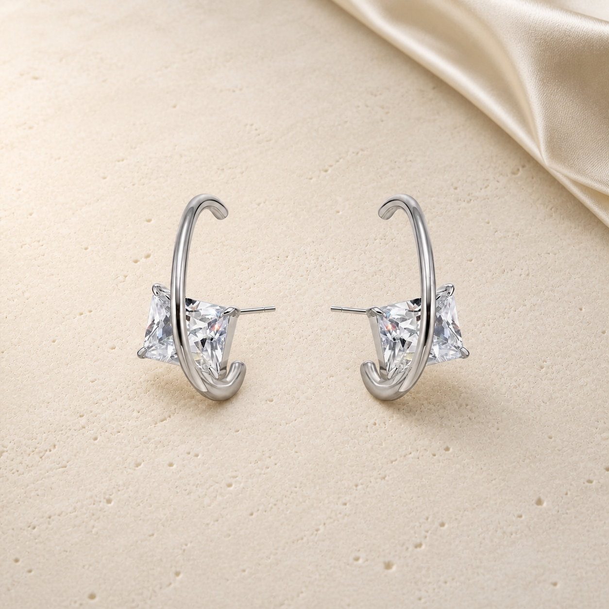 Silver wire triangular zirconia stud earrings on ivory travertine