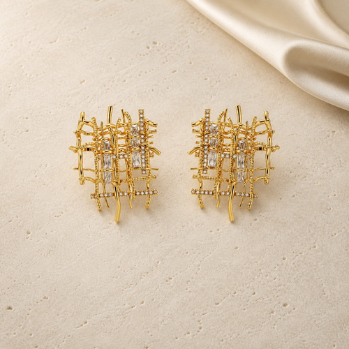 Gold handwoven asymmetric zircon stud earrings on ivory travertine