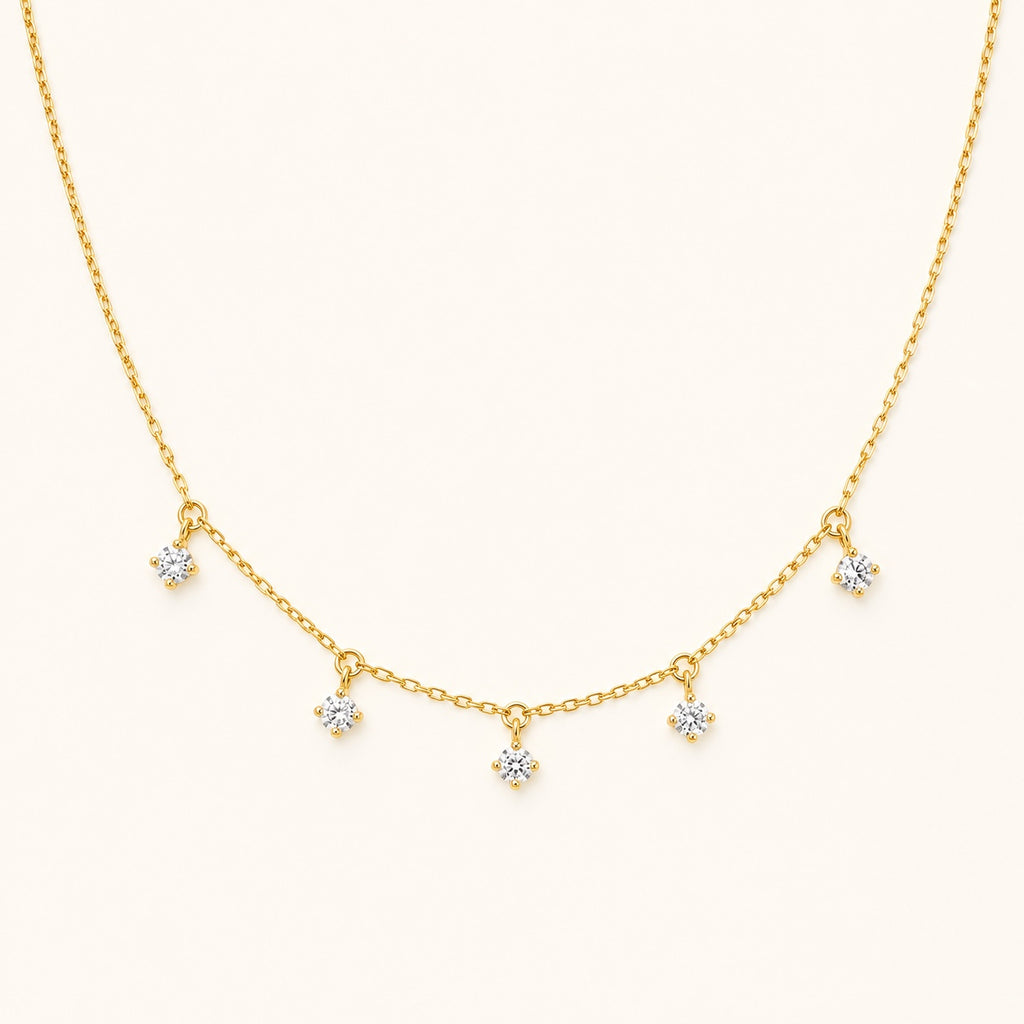 Aurelia Five-Stone Gold Necklace with five clear drop stones on an ivory background