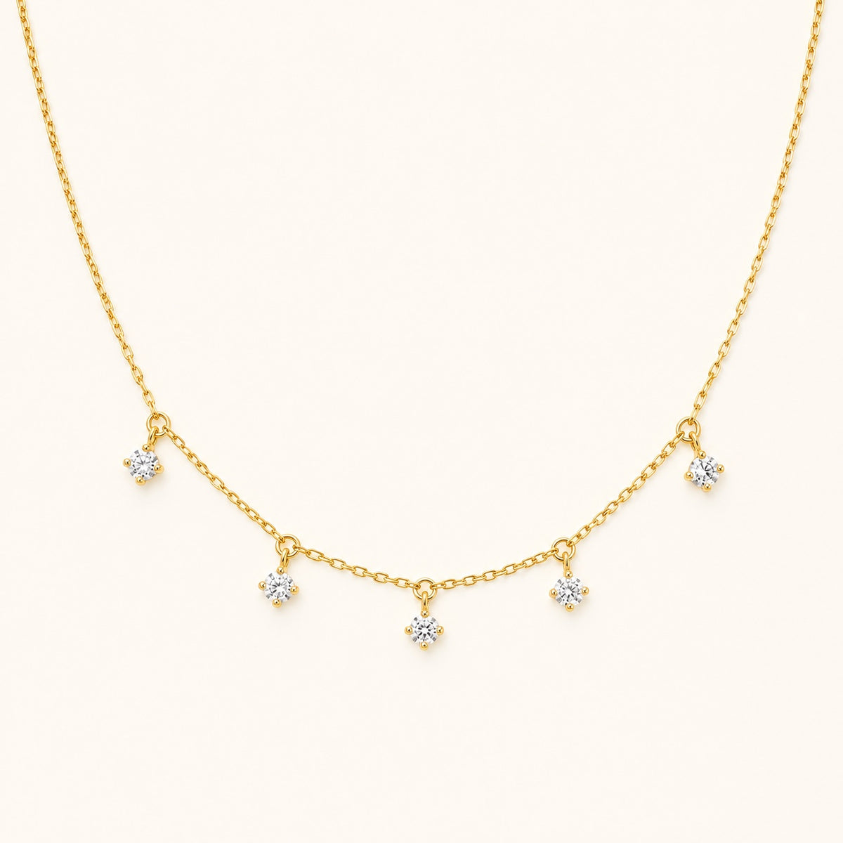 Aurelia Five-Stone Gold Necklace with five clear drop stones on an ivory background