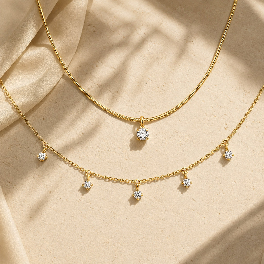 Aurelia Gold Solitaire and Five-Stone Necklace layered on warm stone with soft sunlight