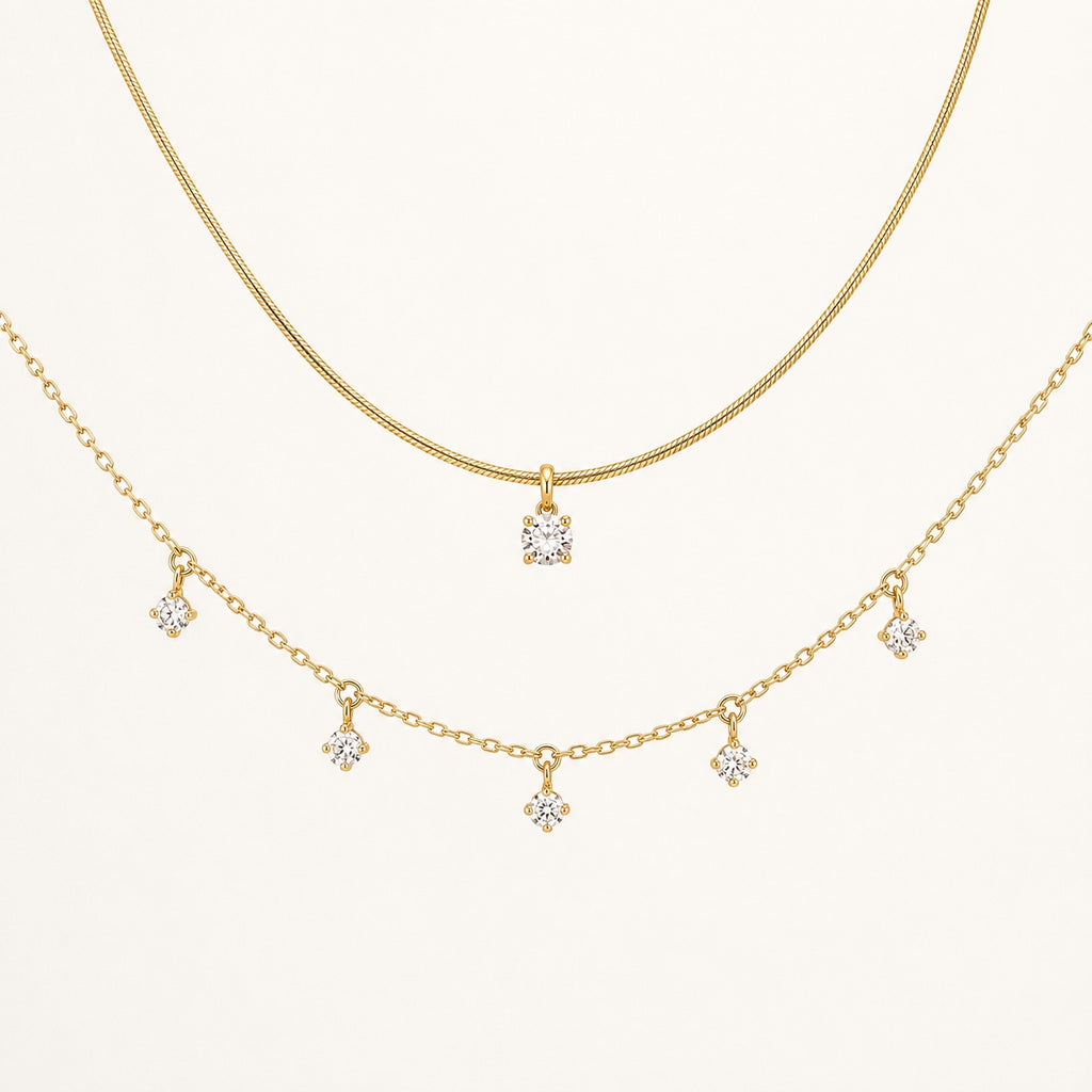 Aurelia Gold Solitaire and Five-Stone Necklace set on a clean ivory background