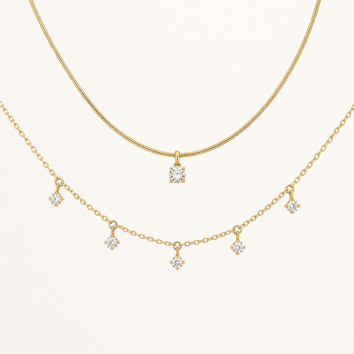 Aurelia Gold Solitaire and Five-Stone Necklace set on a clean ivory background