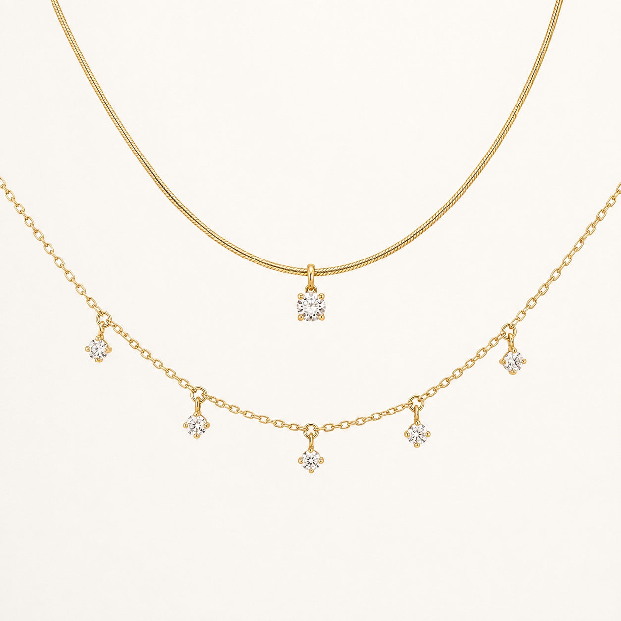Aurelia Gold Solitaire and Five-Stone Necklace set on a clean ivory background