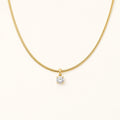 Aurelia Gold Solitaire Necklace with a single clear stone on an ivory background