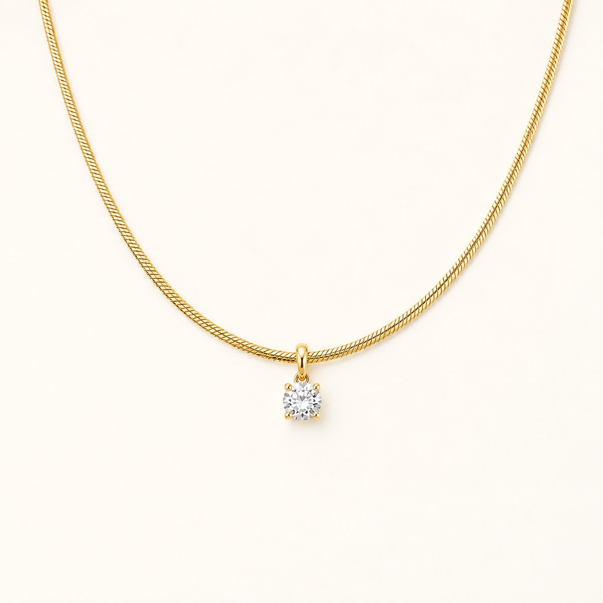 Aurelia Gold Solitaire Necklace with a single clear stone on an ivory background