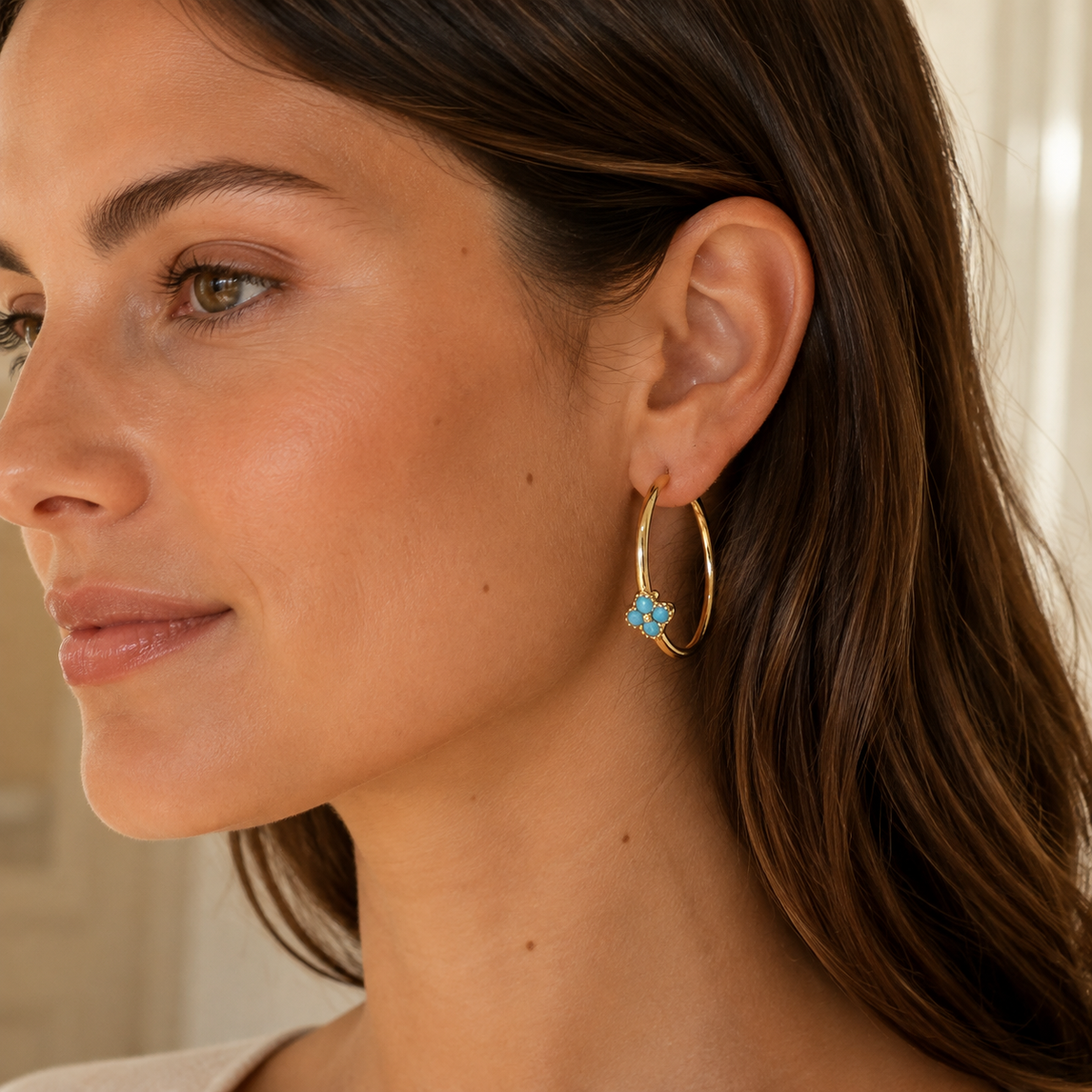 Model wearing Azure Bloom Gold Hoop Earrings with the blue floral detail positioned along the lower hoop.