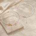 Gold and silver tone crystal butterfly necklaces styled on ivory travertine.