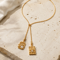 Celestial Duo Lariat Necklace styled on warm ivory travertine with two sculptural crystal pendants.