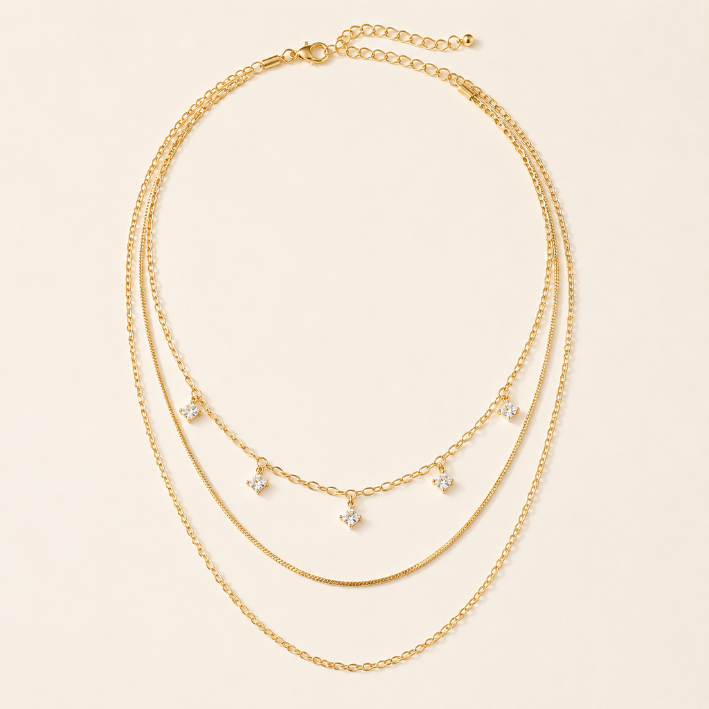 Gold-tone three-layer sterling silver necklace with five square crystals on warm ivory background