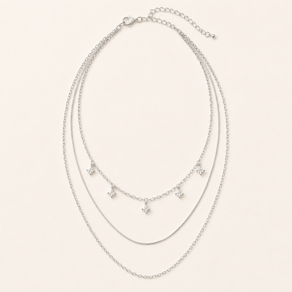 Silver-tone three-layer sterling silver necklace with five square crystals on warm ivory background