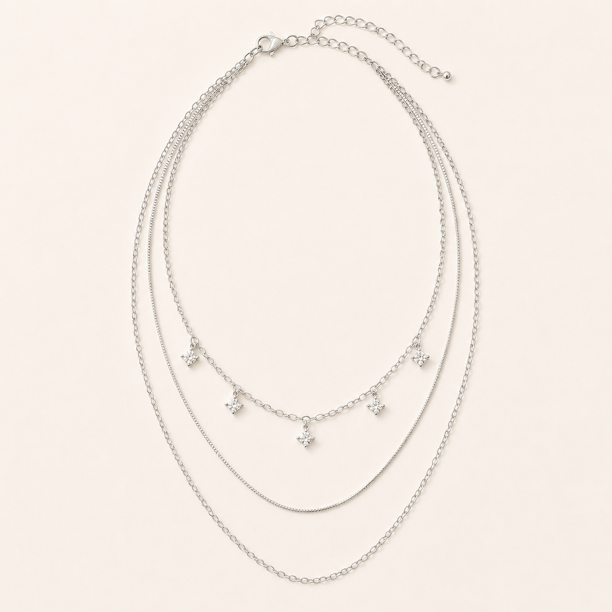 Silver-tone three-layer sterling silver necklace with five square crystals on warm ivory background