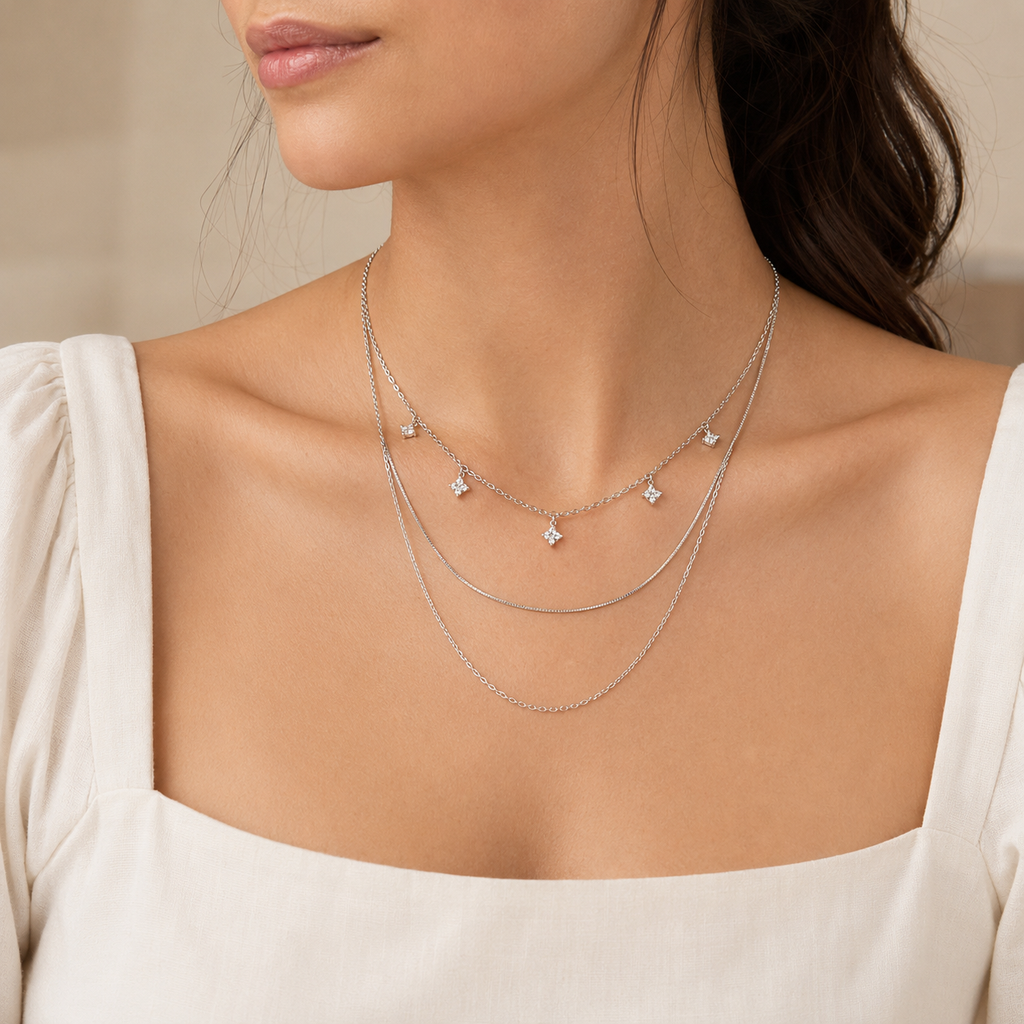 Woman wearing the silver-tone Elara three-layer crystal necklace with an ivory outfit