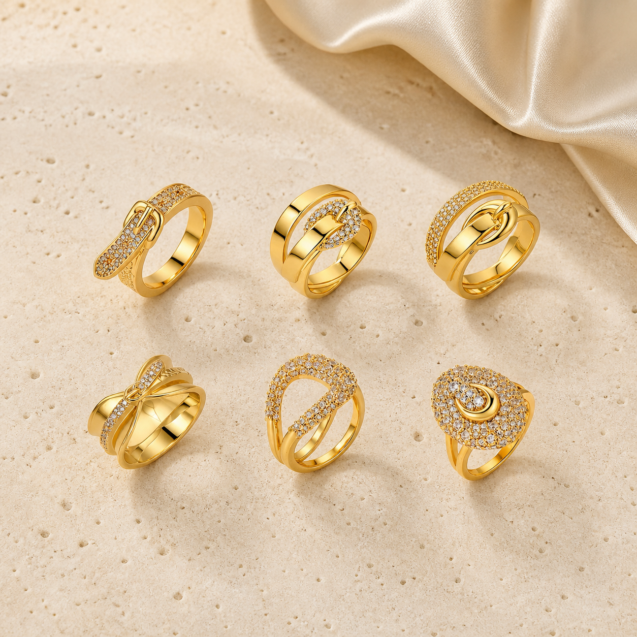 Fortuna Horsebit Ring Collection with six gold ring designs on warm ivory stone