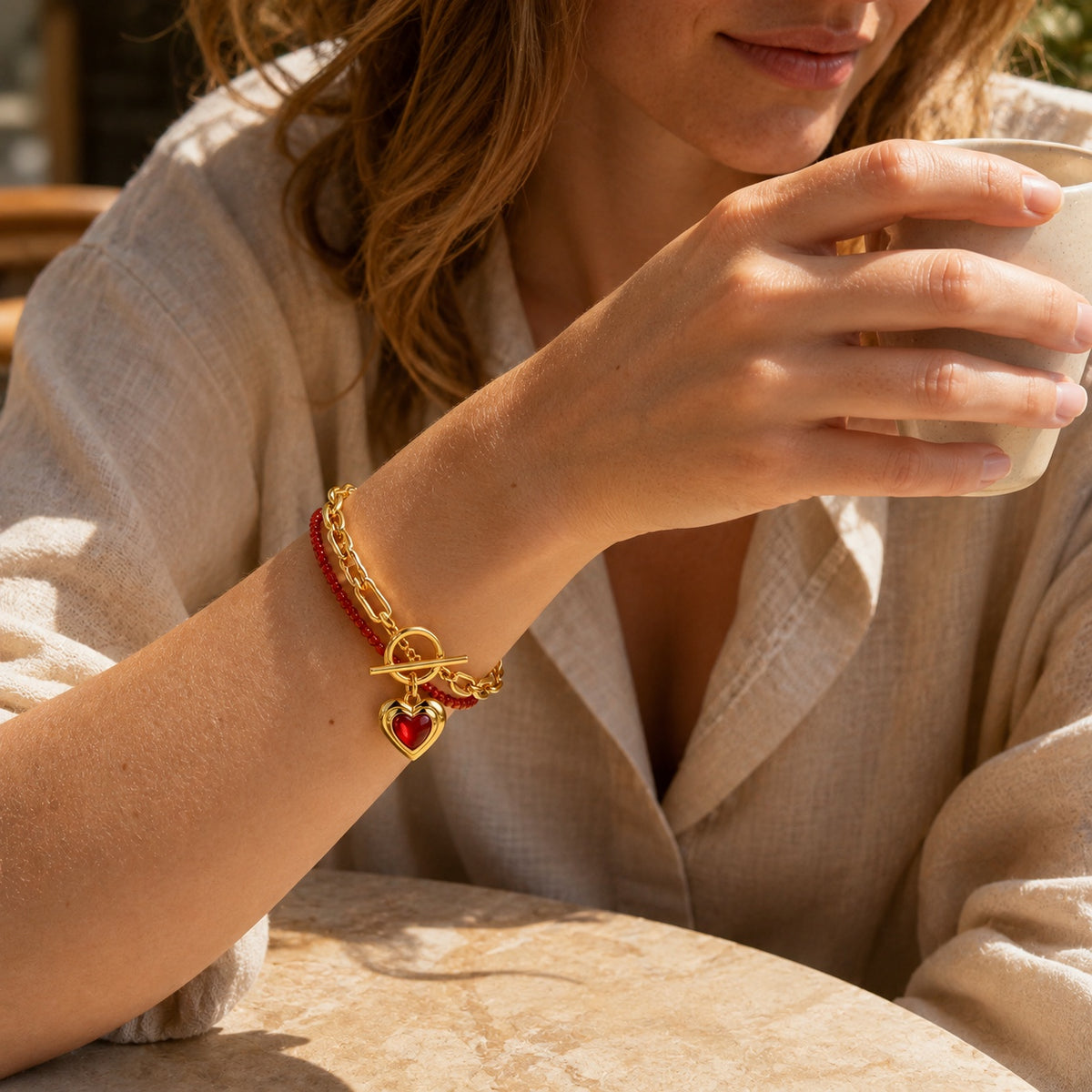 Model wearing Amoura Heart Toggle Bracelet in red agate and gold tone