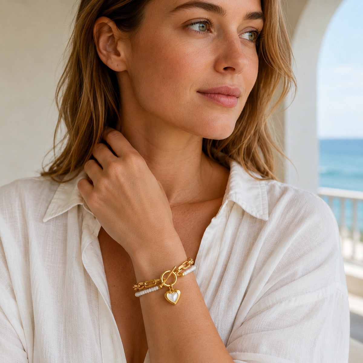 Model wearing Amoura Heart Toggle Bracelet in white shell and gold tone