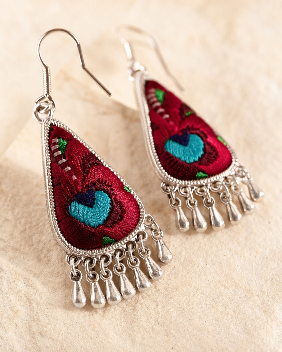 Close-up detail of red floral embroidery and silver-plated fringe