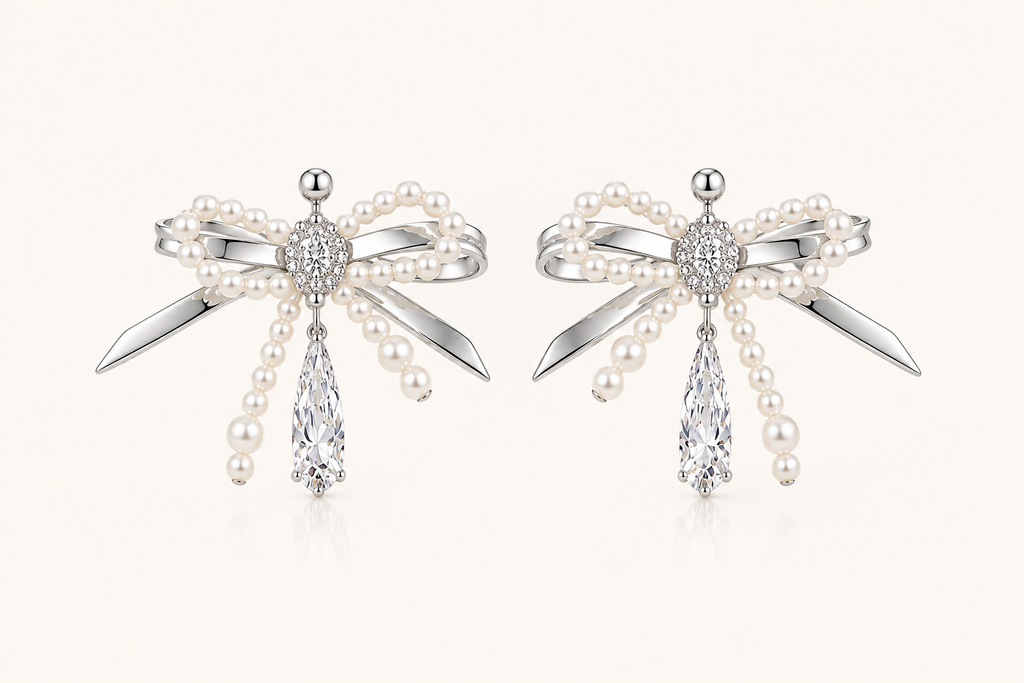 Silver pearl bow cubic zirconia drop earrings on warm ivory background