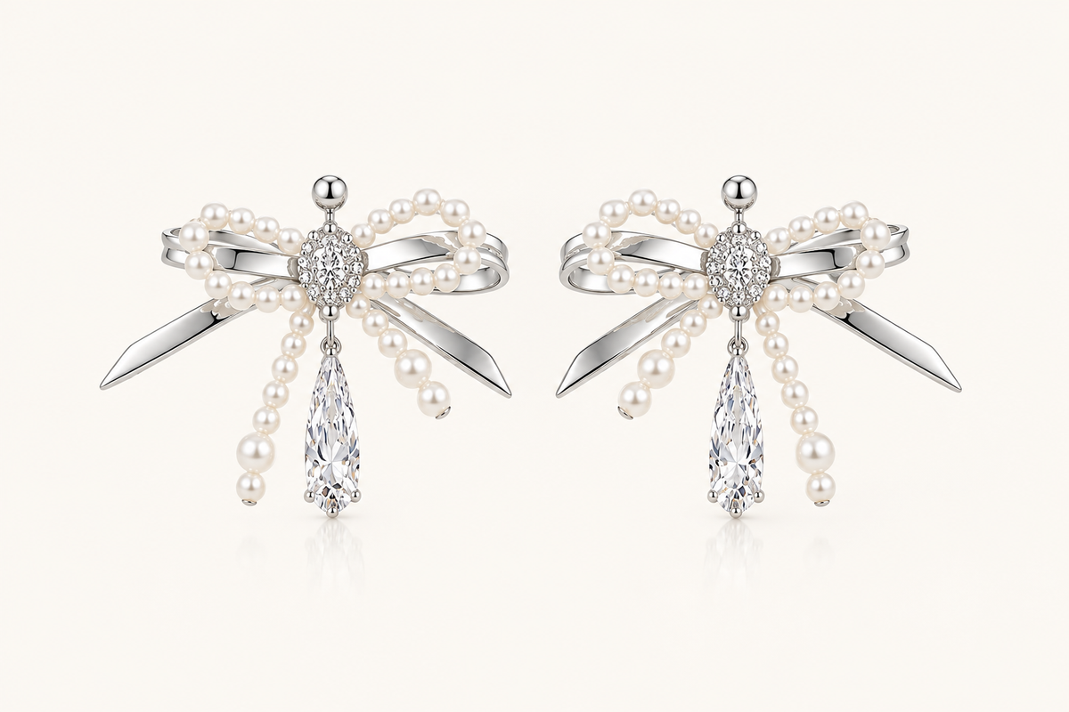 Silver pearl bow cubic zirconia drop earrings on warm ivory background
