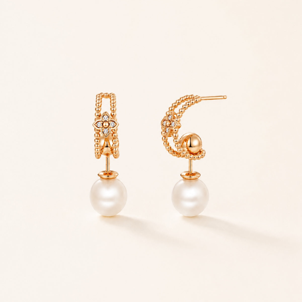 Gold pearl floral drop earrings on warm ivory background