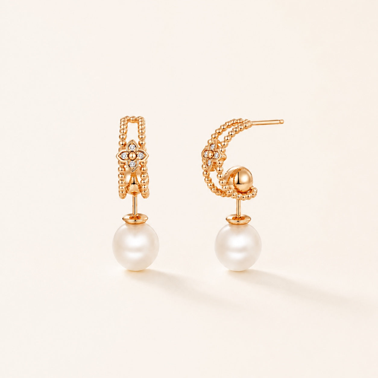 Gold pearl floral drop earrings on warm ivory background