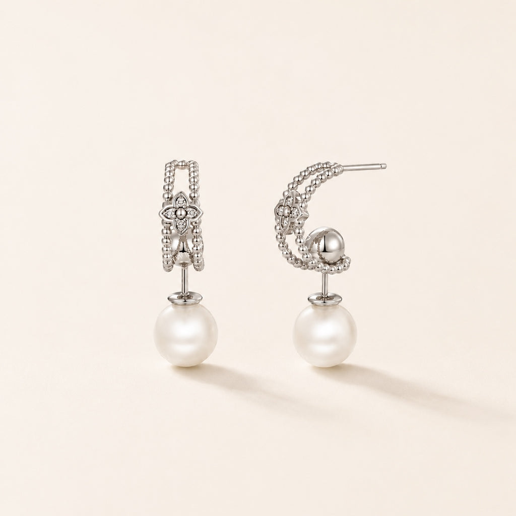 Silver pearl floral drop earrings on warm ivory background
