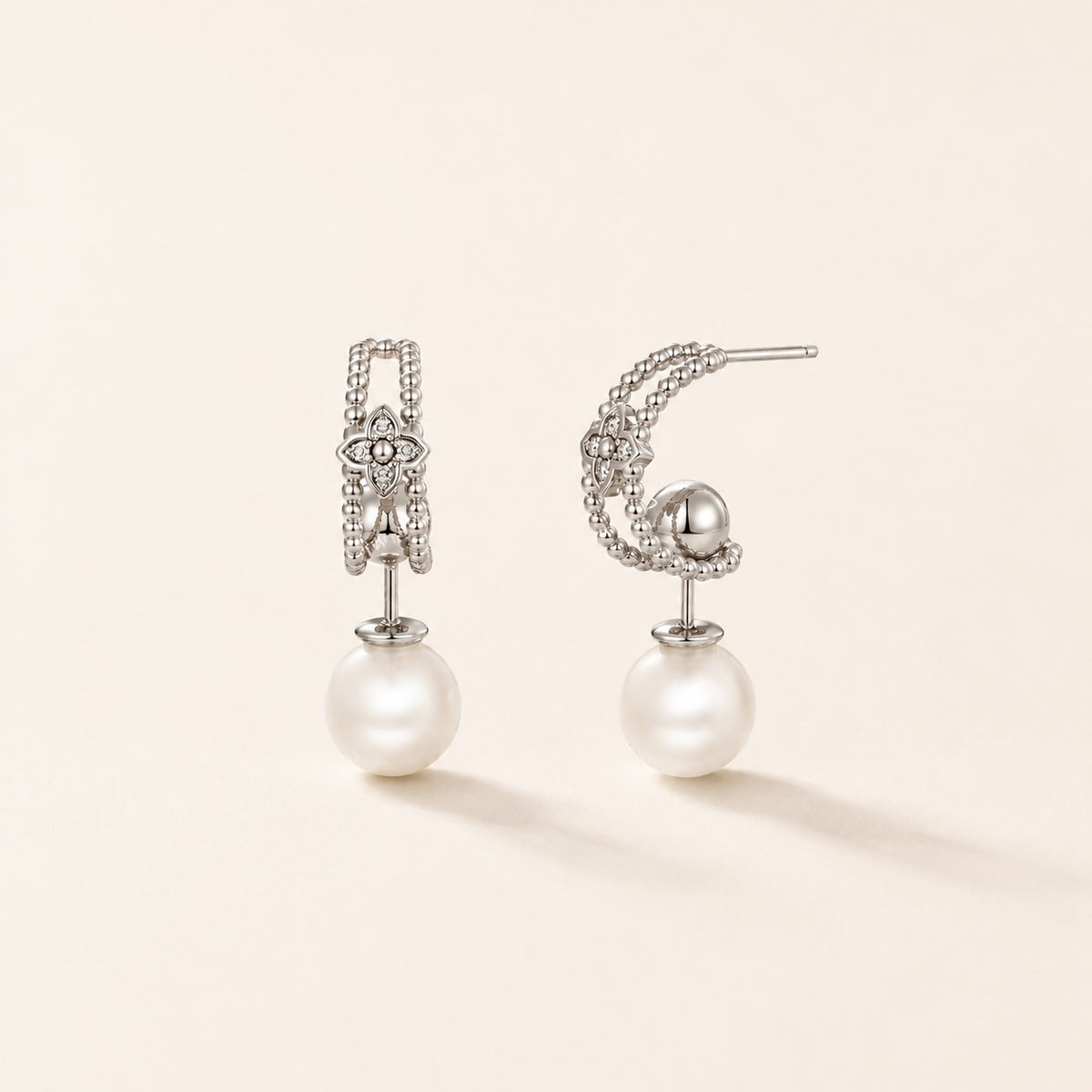 Silver pearl floral drop earrings on warm ivory background