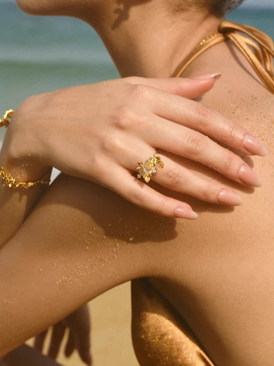 Gold butterfly pearl ring styled on hand by the beach