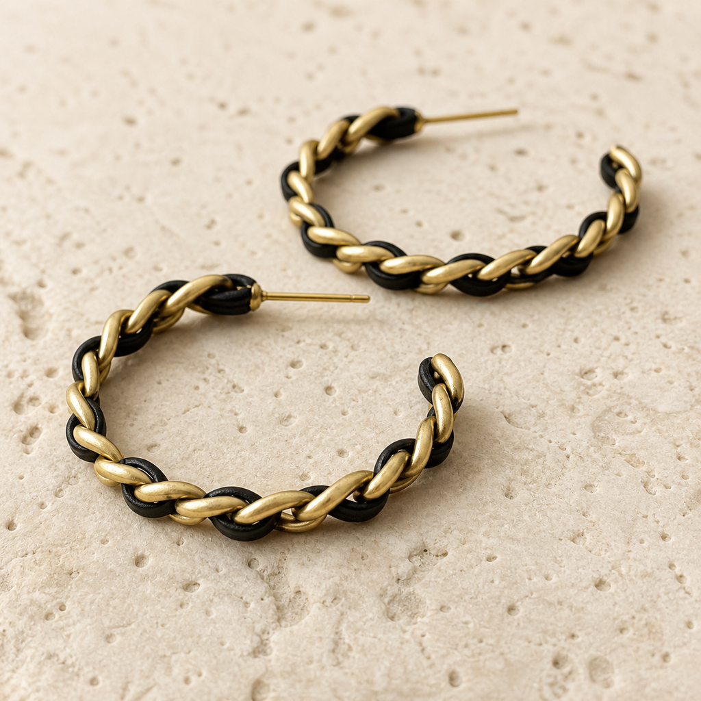 Close-up detail of black and gold-tone woven chain hoop earrings