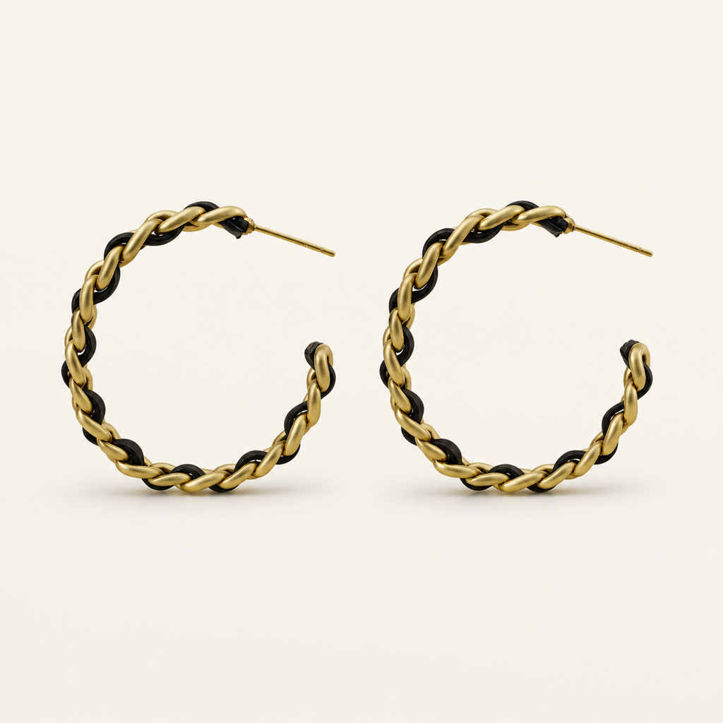 Noir Weave black and gold-tone open hoop earrings on a warm neutral background