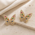 Prism Flutter Butterfly Earrings in gold tone with multicolour cubic zirconia on warm travertine
