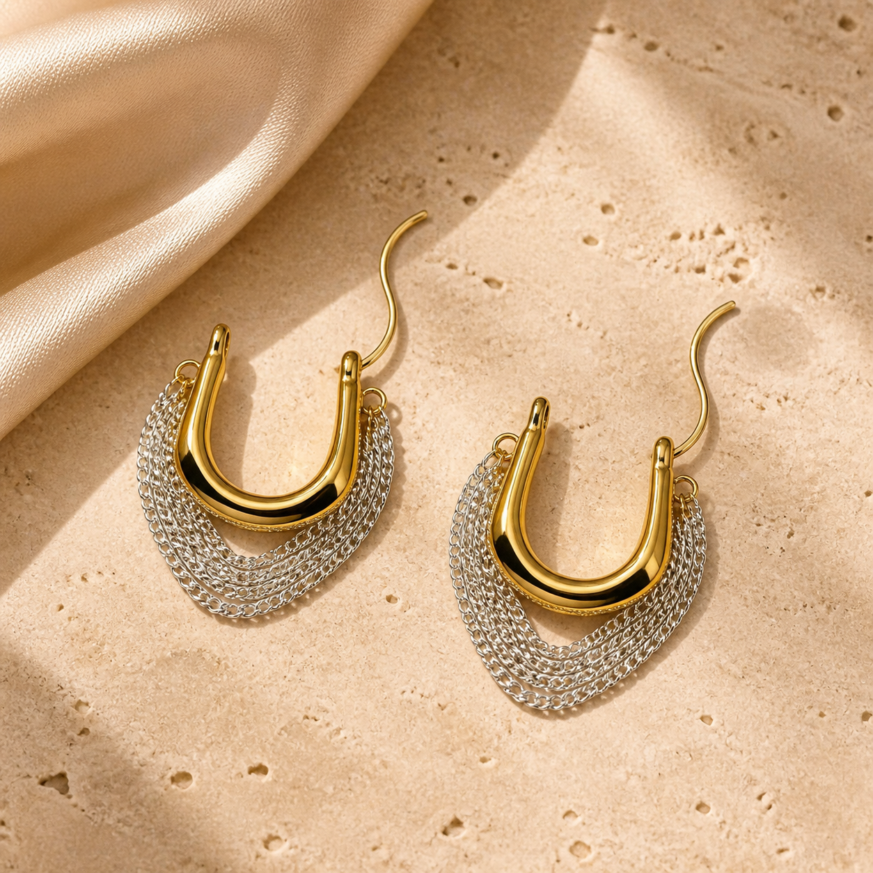 Solara Cascade gold and silver-tone chain hoop earrings on ivory travertine